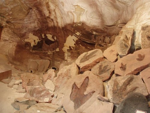 Interior of a cave with colorful rock formations and scattered boulders, showcasing ancient markings on the walls.