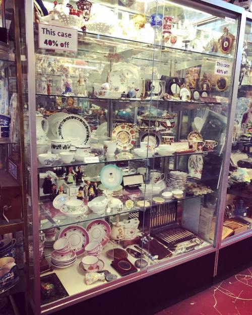 A glass display case filled with various decorative dishes and collectibles, marked with a 40% off sign.