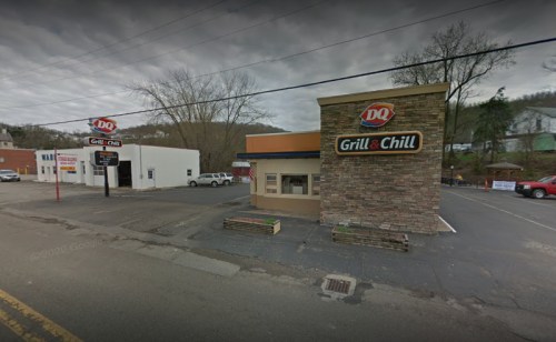 A Dairy Queen Grill & Chill restaurant with a stone facade, located on a street with trees and buildings in the background.
