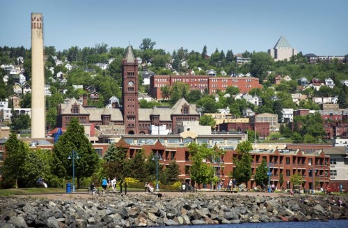 A scenic view of a waterfront city with historic buildings, greenery, and people enjoying the outdoors.