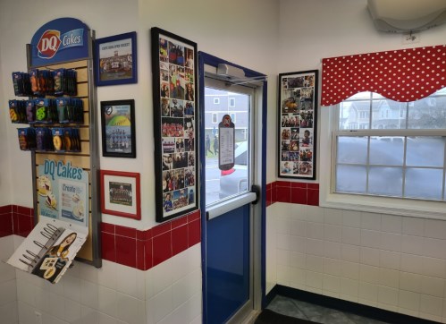 Interior of a DQ store featuring a door, wall decor with photos, and a menu display for DQ cakes.