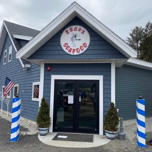 Exterior of Essex Seafood restaurant featuring a blue facade, sign, and potted plants by the entrance.