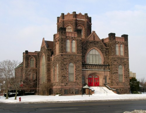 Historic stone building with gothic architecture, featuring red doors and snow-covered surroundings.