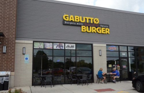 Exterior of Gabutto Burger restaurant featuring outdoor seating and a sign that reads "Burgers with Japanese Twists."