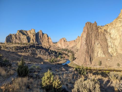 A scenic view of rugged rock formations and a winding river under a clear blue sky.