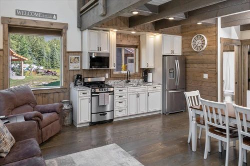 Cozy kitchen with modern appliances, wooden accents, and a dining area, featuring a view of nature outside.