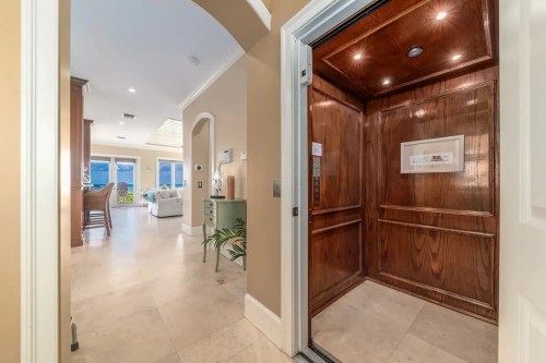 A wooden elevator opens to a bright, modern interior with a view of a living space and outdoor area.