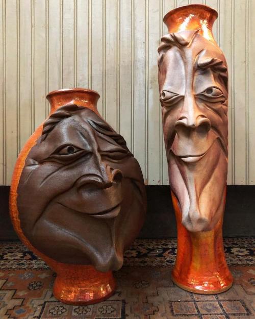 Two artistic vases with exaggerated, whimsical faces, one round and short, the other tall and slender, both in warm colors.