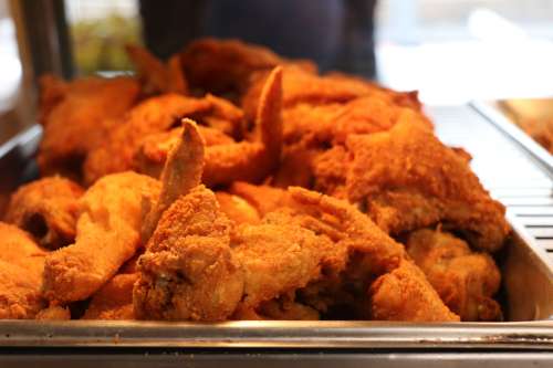 A close-up of a tray filled with golden-brown, crispy fried chicken wings.