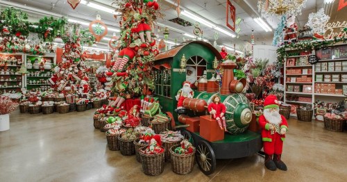 A festive store display featuring a train, Santa figures, and holiday decorations in red and green.