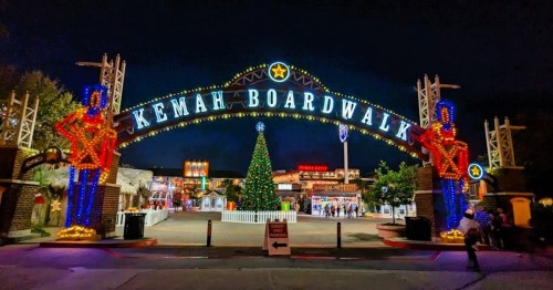 Colorful entrance to Kemah Boardwalk at night, adorned with festive lights and a large Christmas tree in the background.