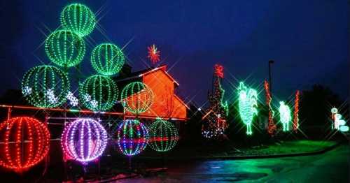 Colorful Christmas lights in various shapes illuminate a dark evening, creating a festive holiday atmosphere.