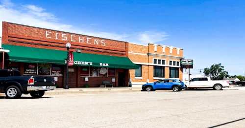 A brick building with "Eischens" sign and green awning, featuring a bar entrance and parked cars in front.