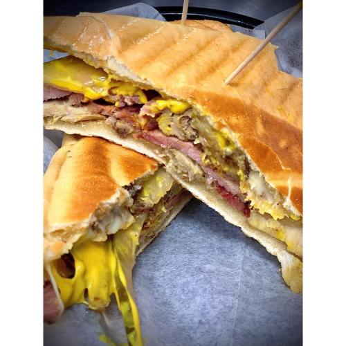A close-up of a delicious sandwich with layers of meat and melted cheese, cut in half and held together with toothpicks.