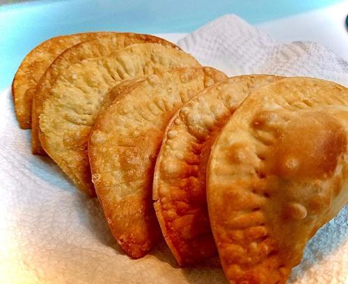 A plate of golden-brown, crispy empanadas arranged neatly on a paper towel.