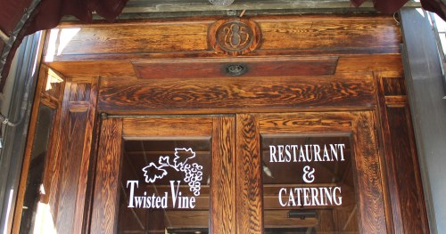 Wooden restaurant entrance with "Twisted Vine" and "Restaurant & Catering" signs.