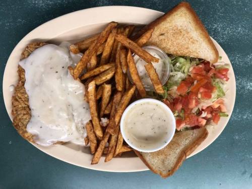 A plate of fried chicken with gravy, French fries, a side salad, and two slices of toast.