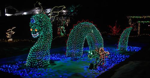 A colorful, illuminated serpent-like creature made of lights, surrounded by blue and green lights in a dark setting.