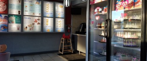 Interior of an ice cream shop featuring a menu board and a glass display case with various treats.