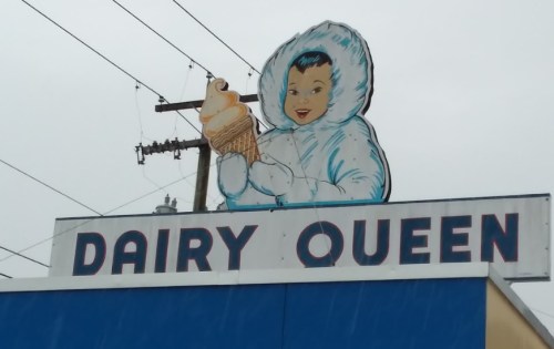 Sign for Dairy Queen featuring a cartoon character in a white parka holding an ice cream cone.