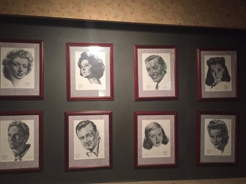 A wall display featuring eight framed black-and-white portraits of classic Hollywood actors and actresses.