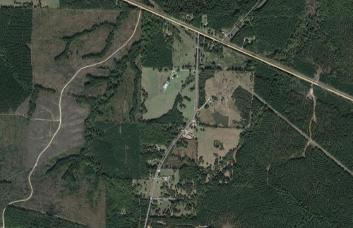 Aerial view of a rural area with fields, roads, and patches of forested land.