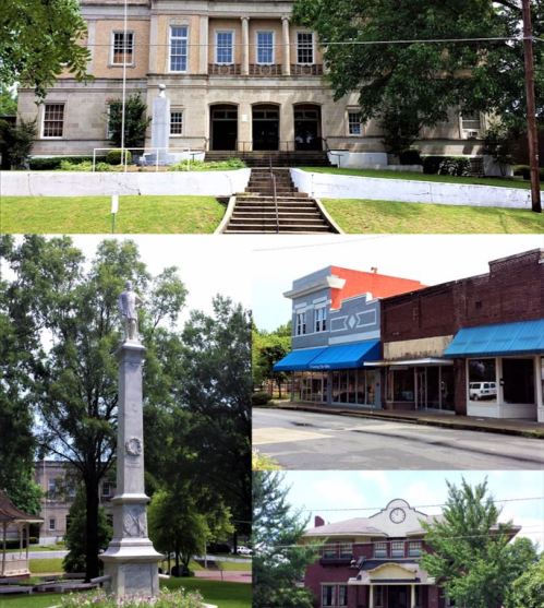 Historic buildings and a monument in a small town, featuring a courthouse, shops, and a statue surrounded by greenery.