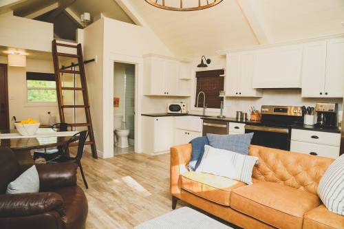 Cozy interior of a modern kitchen and living area with a ladder, sofa, and dining table. Bright and inviting atmosphere.