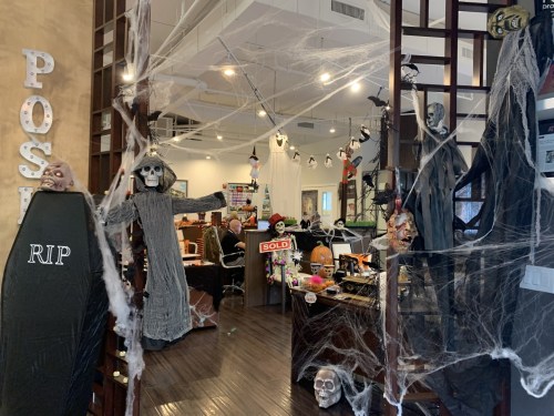An office decorated for Halloween with cobwebs, skeletons, and spooky props, creating a festive atmosphere.