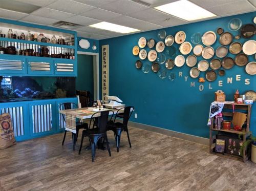 A cozy dining area with teal walls, decorative plates, a fish tank, and a table set for meals.
