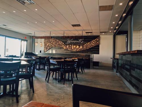 Interior of a modern restaurant featuring wooden decor, tables, and a sign that reads "Bennett's." Bright and inviting atmosphere.