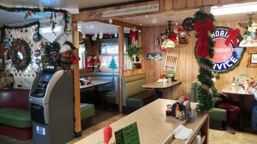 Cozy diner decorated for the holidays with festive wreaths, Santa figures, and a vintage service sign.