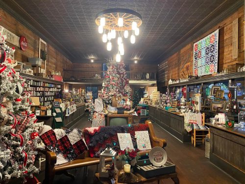 Cozy shop interior decorated for the holidays, featuring a Christmas tree, festive displays, and rustic wooden decor.