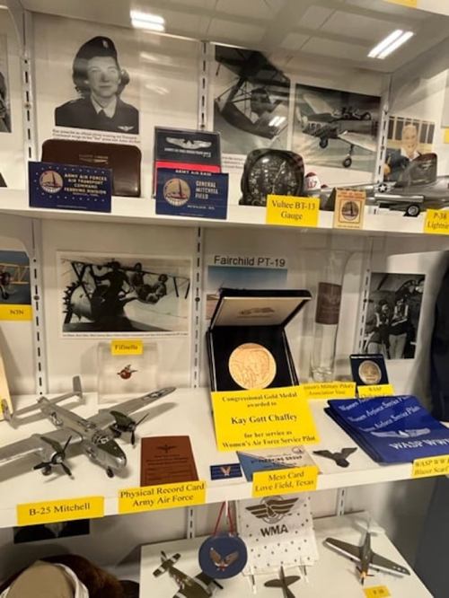 Display case featuring military memorabilia, including aircraft models, medals, and historical photographs.