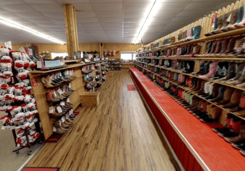 A spacious store interior showcasing rows of colorful boots on shelves, with a wooden floor and bright lighting.