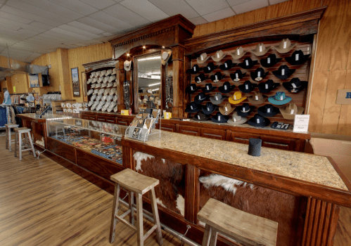 A rustic store interior featuring a wooden counter, shelves of hats, and a display case with various items.