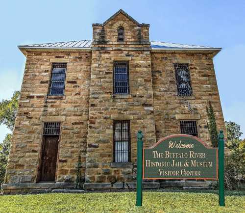 Historic stone building with barred windows, featuring a sign that reads "Welcome to the Buffalo River Historic Jail & Museum."