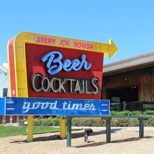 Colorful sign for Kirby Ice House featuring "Beer," "Cocktails," and "Good Times" against a clear blue sky.
