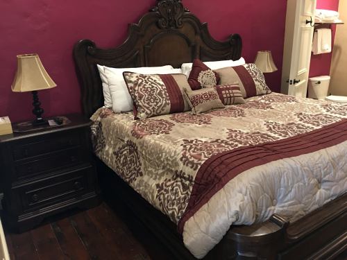 A cozy bedroom featuring a large wooden bed with decorative pillows, a nightstand, and warm-colored walls.