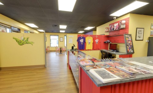 Interior of a colorful shop featuring a reception area, merchandise displays, and seating in a bright, inviting space.