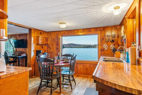 Cozy wooden interior of a lakeside cabin with a dining area, large window, and scenic water view.