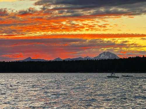 A vibrant sunset over a lake, with mountains in the background and colorful clouds reflecting on the water.