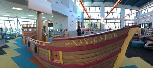 A colorful library interior featuring a large wooden ship structure labeled "S. Navigator."