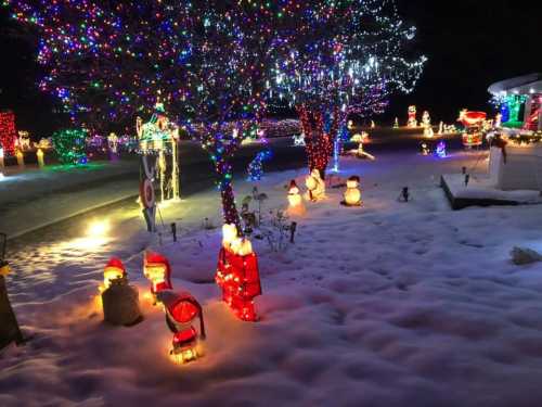 A festive scene with colorful Christmas lights, snow-covered ground, and illuminated decorations like snowmen and Santa figures.