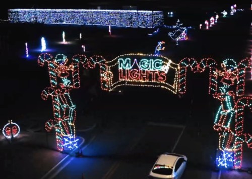 Colorful holiday lights form an archway reading "Magic Lights," illuminating a festive nighttime scene.