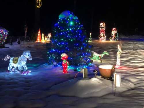 A snowy scene with colorful holiday lights, including a decorated tree, a horse, and various festive figures.