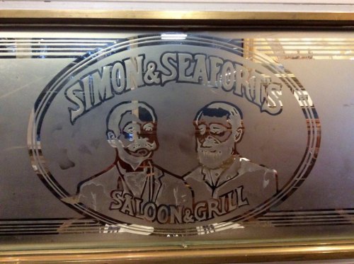 Frosted glass sign featuring two men with mustaches, labeled "Simon & Seafort's Saloon & Grill."