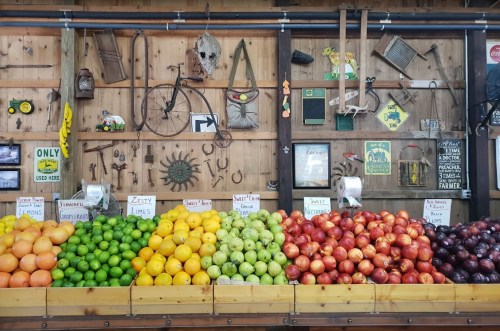 A colorful display of fruits, including apples, lemons, and limes, against a rustic wooden wall with vintage decor.