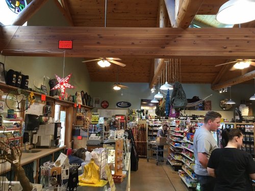 Interior of a store with wooden beams, shelves filled with various products, and customers browsing.