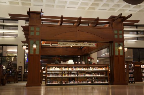 A wooden library structure with a sign and bookshelves filled with books, illuminated by soft lighting.